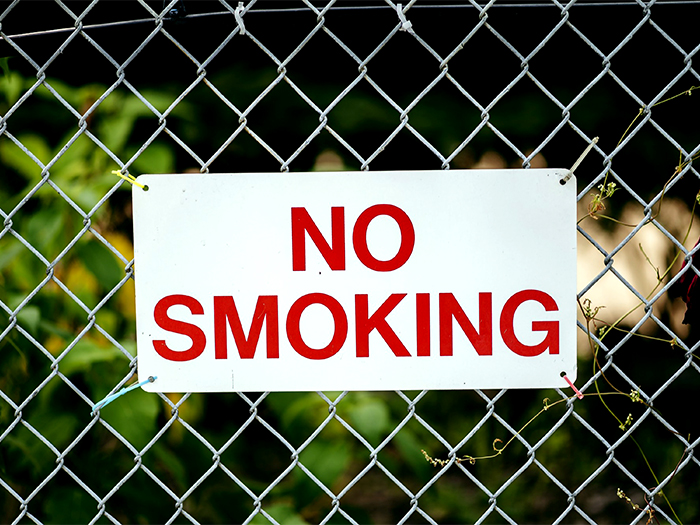 closeup focus shot no smoking sign hanging by fence